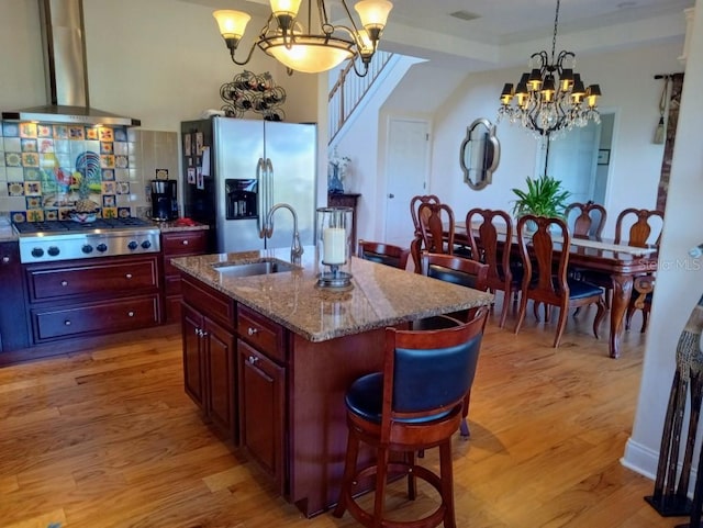 6926 Mccray Dr, Hudson, FL 34667 - kitchen featuring stainless steel appliances, wall chimney exhaust hood, a chandelier, a sink, and light wood-style flooring