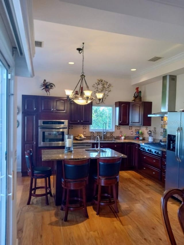 6926 Mccray Dr, Hudson, FL 34667 - kitchen featuring appliances with stainless steel finishes, wall chimney exhaust hood, light wood-type flooring, a breakfast bar area, and crown molding