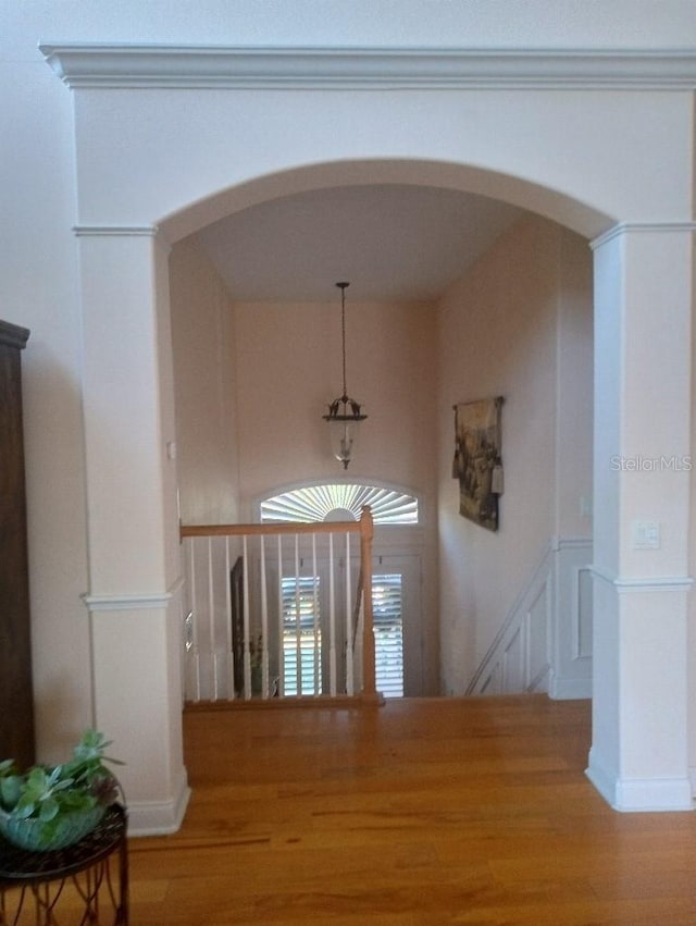 6926 Mccray Dr, Hudson, FL 34667 - hallway with arched walkways, wood finished floors, a decorative wall, wainscoting, and an upstairs landing