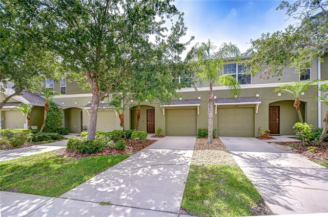 multi unit property with stucco siding, concrete driveway, and an attached garage