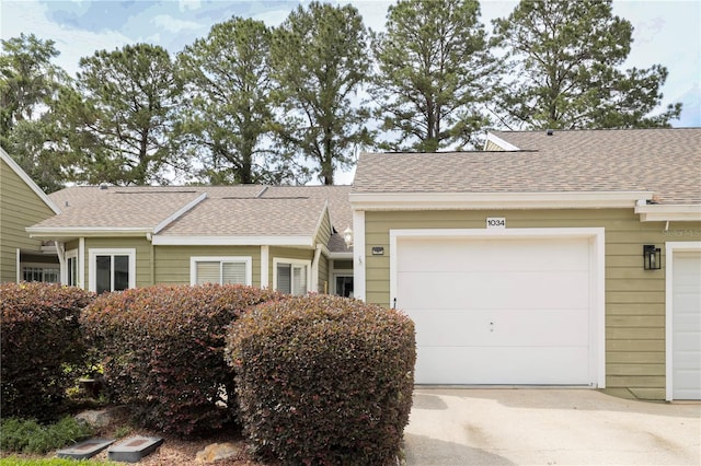 ranch-style home with concrete driveway and roof with shingles