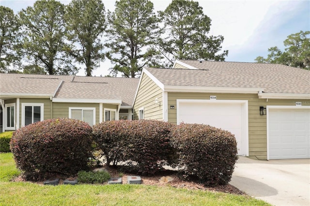 view of front of house with concrete driveway, roof with shingles, and an attached garage