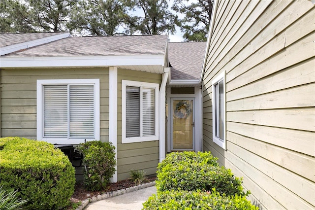 doorway to property with roof with shingles