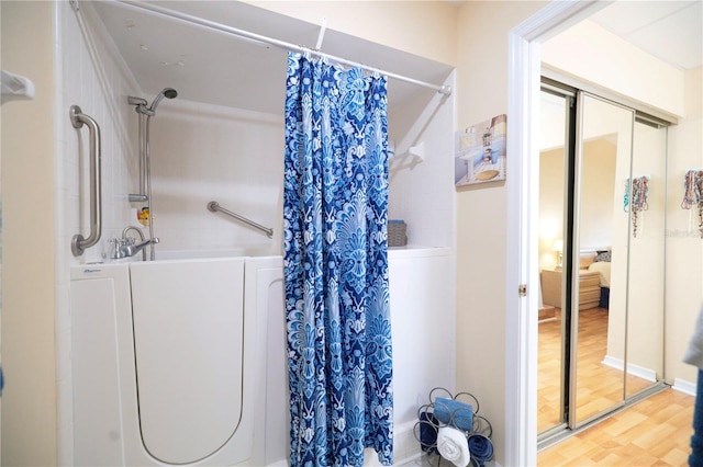 full bath with washer / dryer, a shower with shower curtain, and wood finished floors