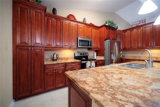 kitchen featuring a sink, reddish brown cabinets, light stone countertops, appliances with stainless steel finishes, and lofted ceiling