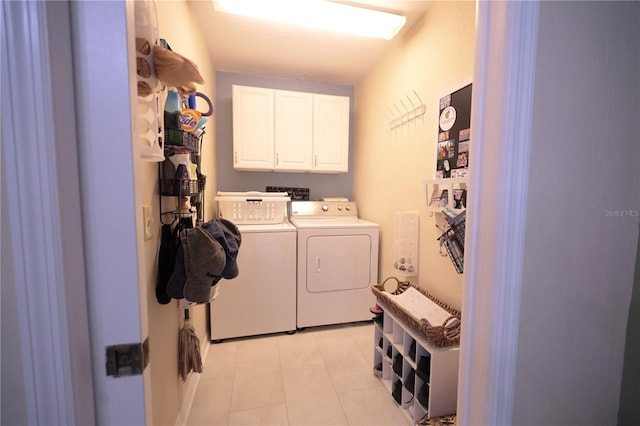 laundry room with washer and clothes dryer, cabinet space, and light tile patterned floors