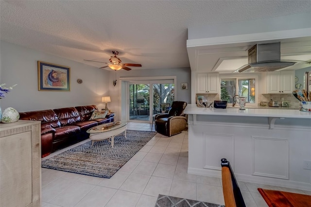living room featuring a ceiling fan, light tile patterned floors, and a textured ceiling