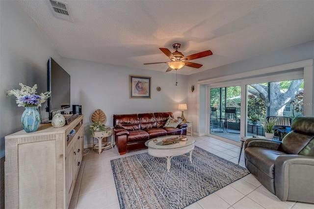 living room with ceiling fan, a textured ceiling, light tile patterned floors, and baseboards