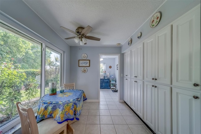 dining room with a ceiling fan, light tile patterned floors, a textured ceiling, and baseboards