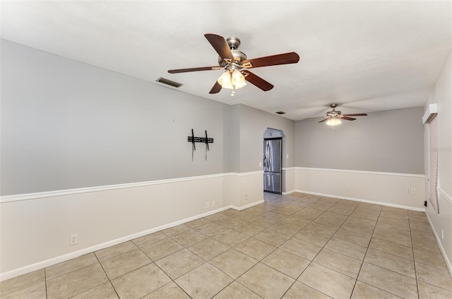 spare room featuring light tile patterned floors, ceiling fan, baseboards, and visible vents