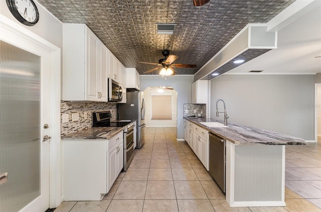kitchen featuring a sink, ceiling fan, appliances with stainless steel finishes, decorative backsplash, and light tile patterned flooring