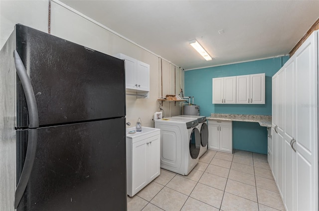 washroom with light tile patterned floors, independent washer and dryer, cabinet space, and gas water heater