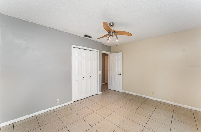 unfurnished bedroom featuring light tile patterned floors, baseboards, a closet, and visible vents