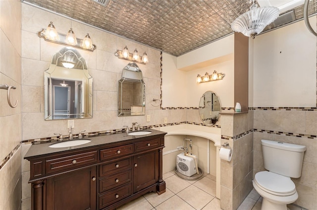 bathroom with a sink, tile walls, toilet, and tile patterned floors