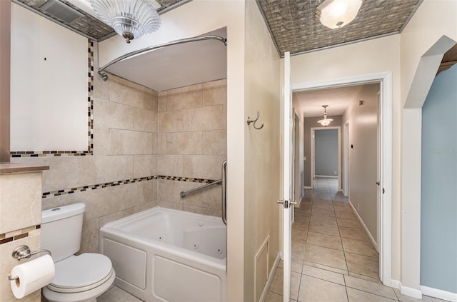 bathroom with a combined bath / shower with jetted tub, toilet, tile patterned flooring, and baseboards