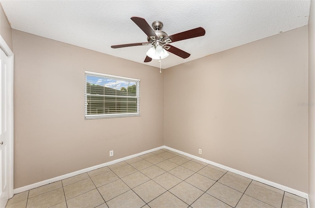 empty room with ceiling fan, a textured ceiling, baseboards, and light tile patterned floors