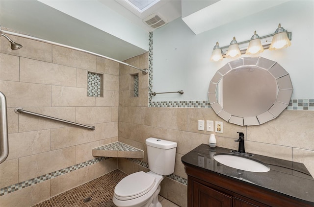 bathroom with vanity, toilet, visible vents, and tiled shower