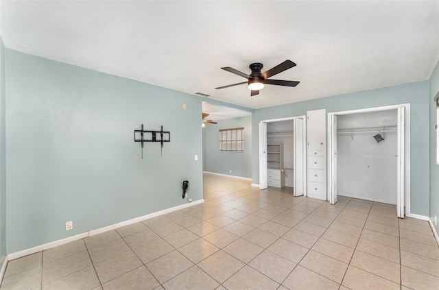 unfurnished bedroom featuring light tile patterned floors, baseboards, ceiling fan, visible vents, and two closets