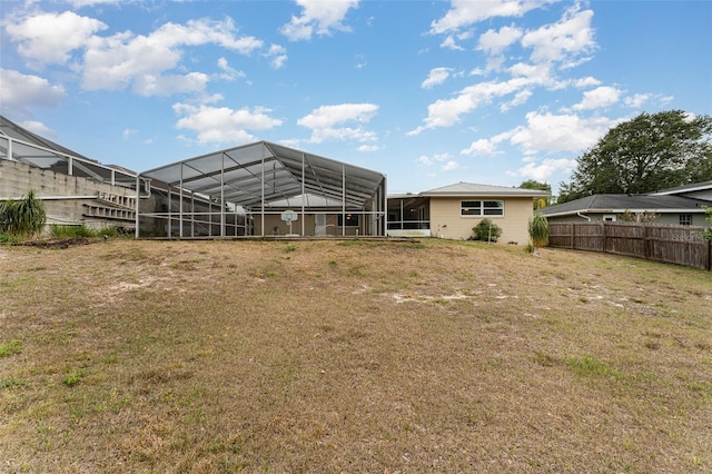 back of house with a yard, fence, and a lanai