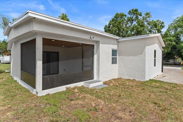 3215 E Powhatan Ave, Tampa, FL 33610 - back of property with a sunroom, stucco siding, and a lawn