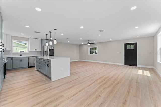 3215 E Powhatan Ave, Tampa, FL 33610 - kitchen with stainless steel appliances, gray cabinetry, a center island, healthy amount of natural light, and recessed lighting