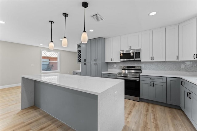 3215 E Powhatan Ave, Tampa, FL 33610 - kitchen featuring stainless steel appliances, gray cabinetry, light wood-style flooring, a kitchen island, and recessed lighting