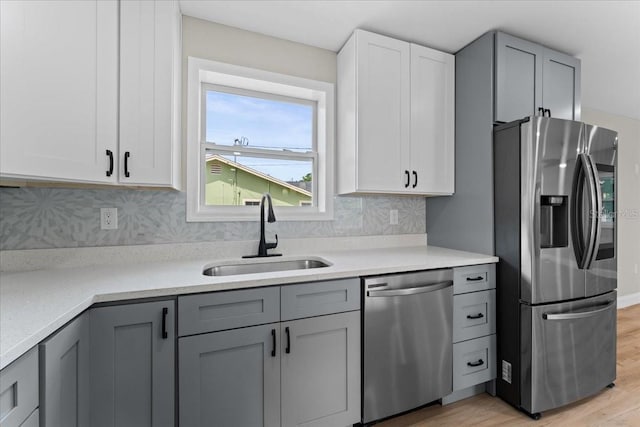3215 E Powhatan Ave, Tampa, FL 33610 - kitchen featuring appliances with stainless steel finishes, a sink, light wood-type flooring, gray cabinets, and light countertops