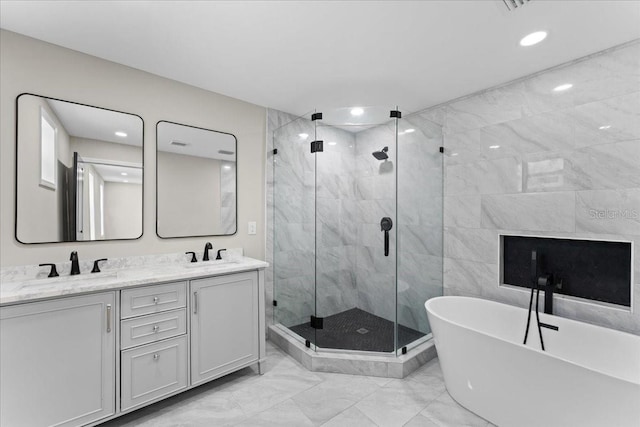 3215 E Powhatan Ave, Tampa, FL 33610 - bathroom featuring marble look tiles, a shower stall, a freestanding bath, double vanity, and recessed lighting
