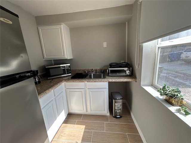 kitchen featuring white cabinetry, stainless steel appliances, a toaster, and a sink