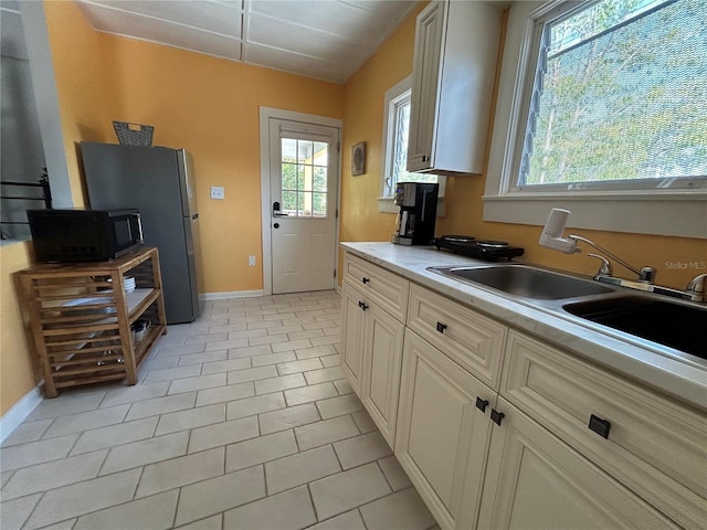 kitchen with baseboards, a healthy amount of sunlight, black microwave, and light countertops