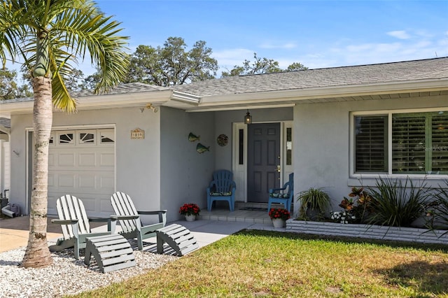 entrance to property featuring stucco siding, a garage, roof with shingles, and a yard
