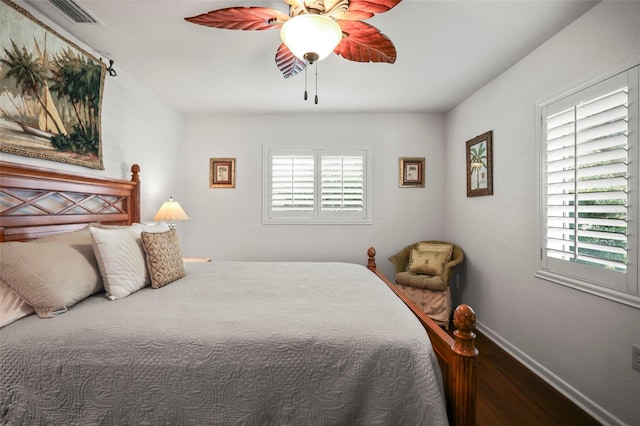 bedroom featuring multiple windows, wood finished floors, baseboards, and ceiling fan