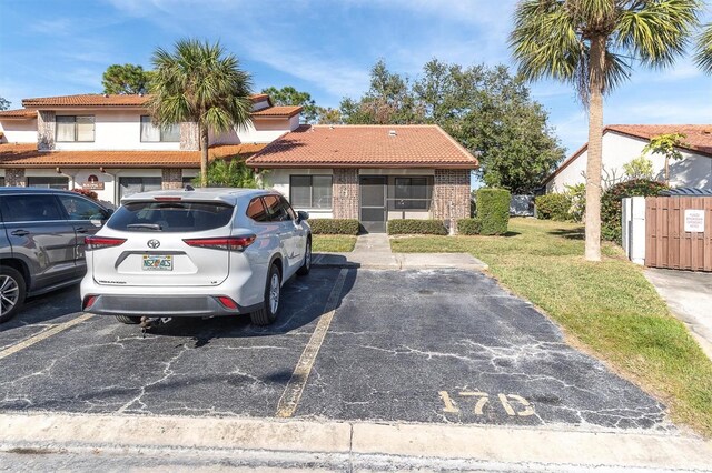 7360 Ulmerton Rd Unit 17D, Largo, FL 33771 - view of front facade with a tiled roof, stucco siding, a front lawn, uncovered parking, and brick siding