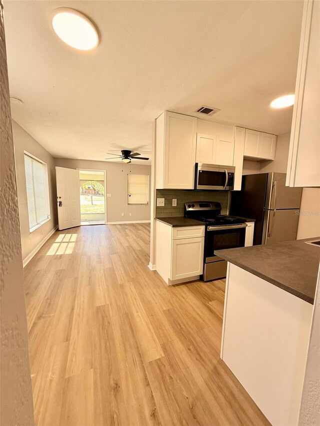 2201 Flamingo Ave, Deltona, FL 32738 - kitchen featuring stainless steel appliances, dark countertops, white cabinetry, ceiling fan, and light wood-type flooring
