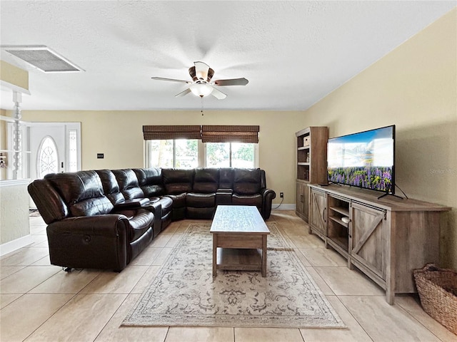 living room featuring a ceiling fan, light tile patterned flooring, visible vents, and a textured ceiling