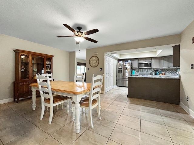 dining space with light tile patterned floors, baseboards, and ceiling fan
