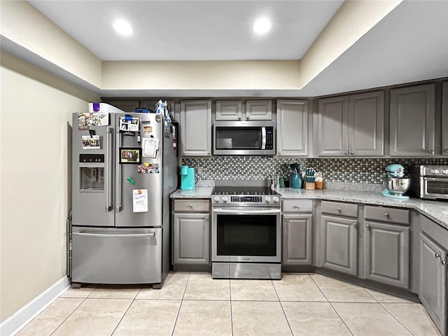 kitchen with stainless steel appliances, decorative backsplash, and gray cabinets