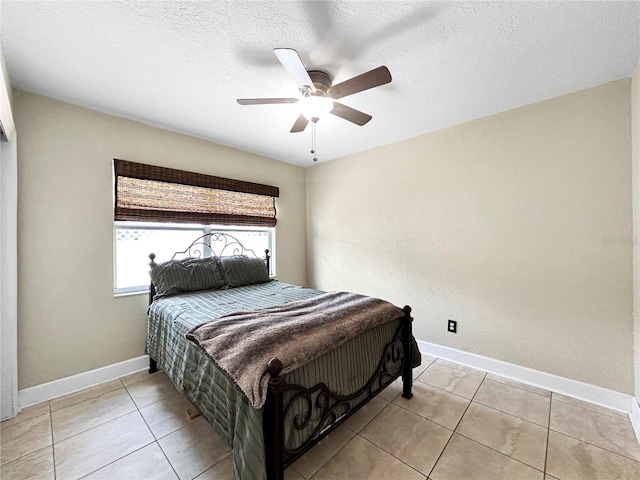 bedroom featuring a textured ceiling, baseboards, light tile patterned flooring, and ceiling fan