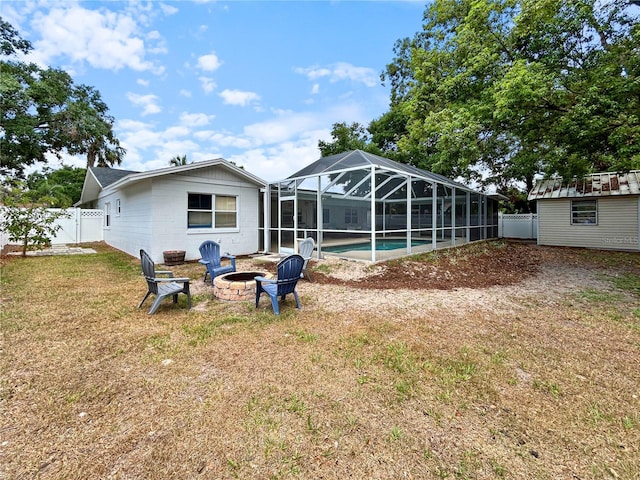back of house with a yard, an outdoor pool, an outdoor fire pit, a fenced backyard, and a lanai