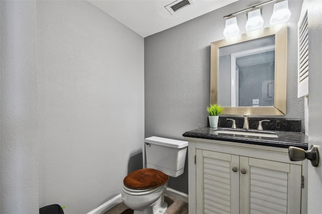 bathroom featuring toilet, baseboards, visible vents, vanity, and a textured wall