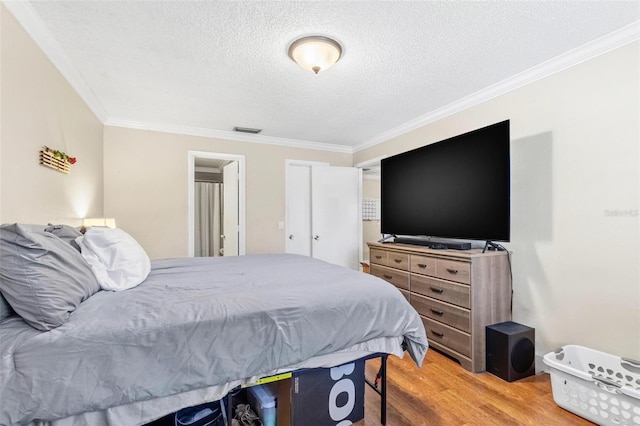 3823 N Oak Dr Unit K22, Tampa, FL 33611 - bedroom with light wood-type flooring, crown molding, visible vents, and a textured ceiling