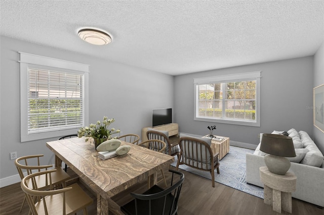 dining area featuring plenty of natural light, dark wood-style flooring, a textured ceiling, and baseboards