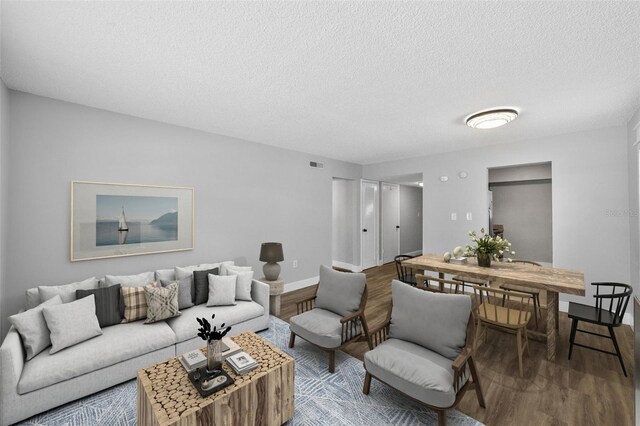 living room with wood finished floors, a textured ceiling, and baseboards