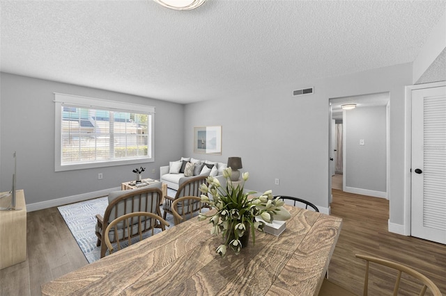 dining space with a textured ceiling, wood finished floors, and baseboards