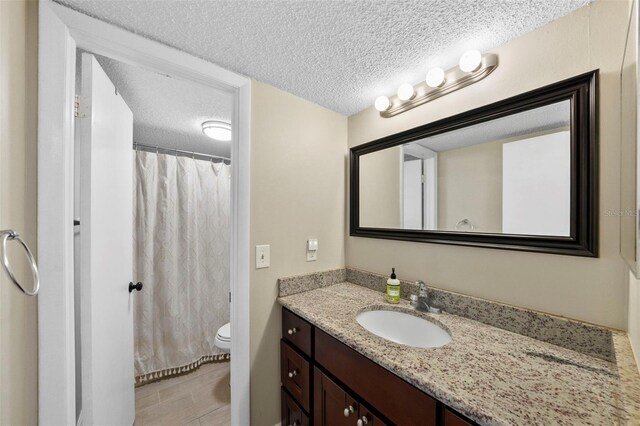 bathroom with toilet, a textured ceiling, vanity, and a shower with curtain