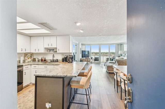 500 Treasure Island Cswy Unit 607, Treasure Island, FL 33706 - kitchen featuring a sink, stove, a textured ceiling, a peninsula, and white cabinets