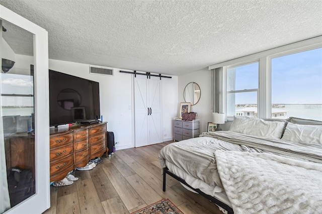 500 Treasure Island Cswy Unit 607, Treasure Island, FL 33706 - bedroom with a barn door, hardwood / wood-style flooring, a textured ceiling, and a water view