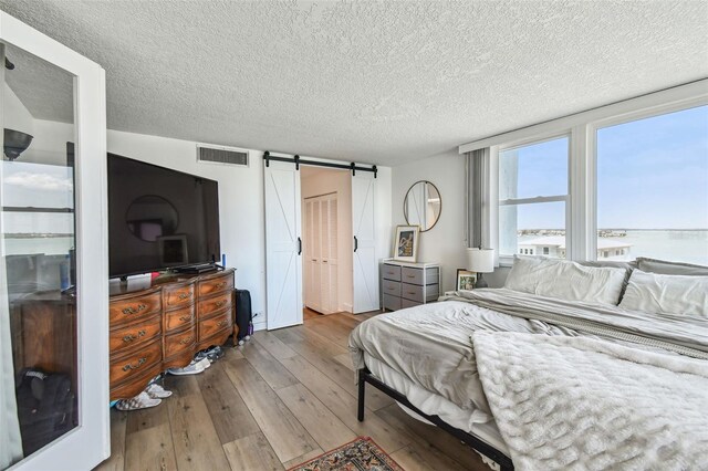 500 Treasure Island Cswy Unit 607, Treasure Island, FL 33706 - bedroom featuring a barn door, hardwood / wood-style flooring, a textured ceiling, and a water view