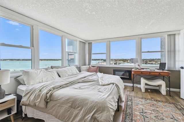 500 Treasure Island Cswy Unit 607, Treasure Island, FL 33706 - bedroom with a water view, wood finished floors, and a textured ceiling