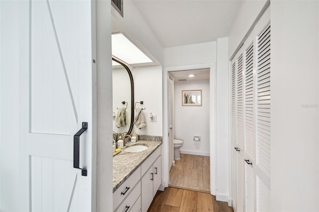 500 Treasure Island Cswy Unit 607, Treasure Island, FL 33706 - bathroom with toilet, a closet, vanity, wood finished floors, and baseboards